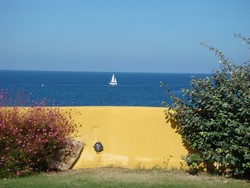 Gelbe Mauer vor dem Meer mit Segelboot
